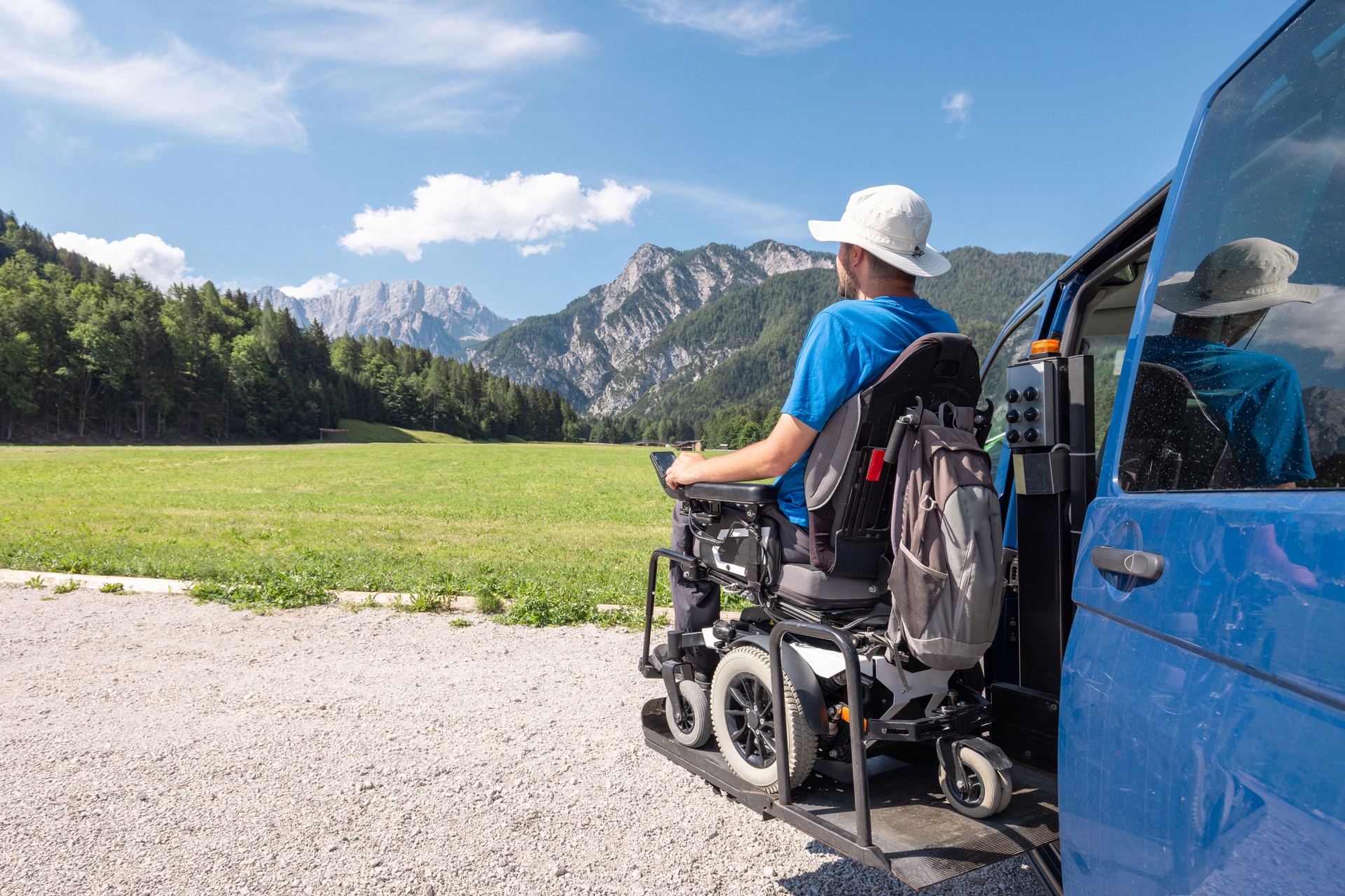 Man with disability getting off a van, using a wheelchair lift