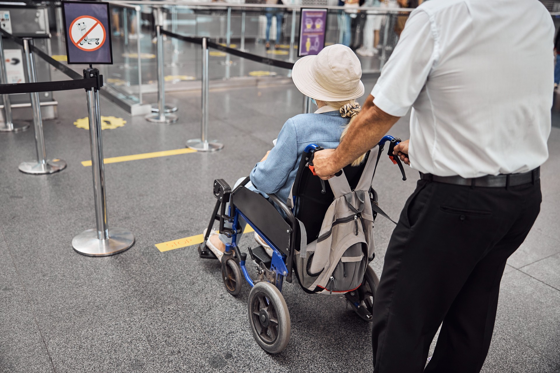 Airline worker rolling a wheelchair with a senior lady