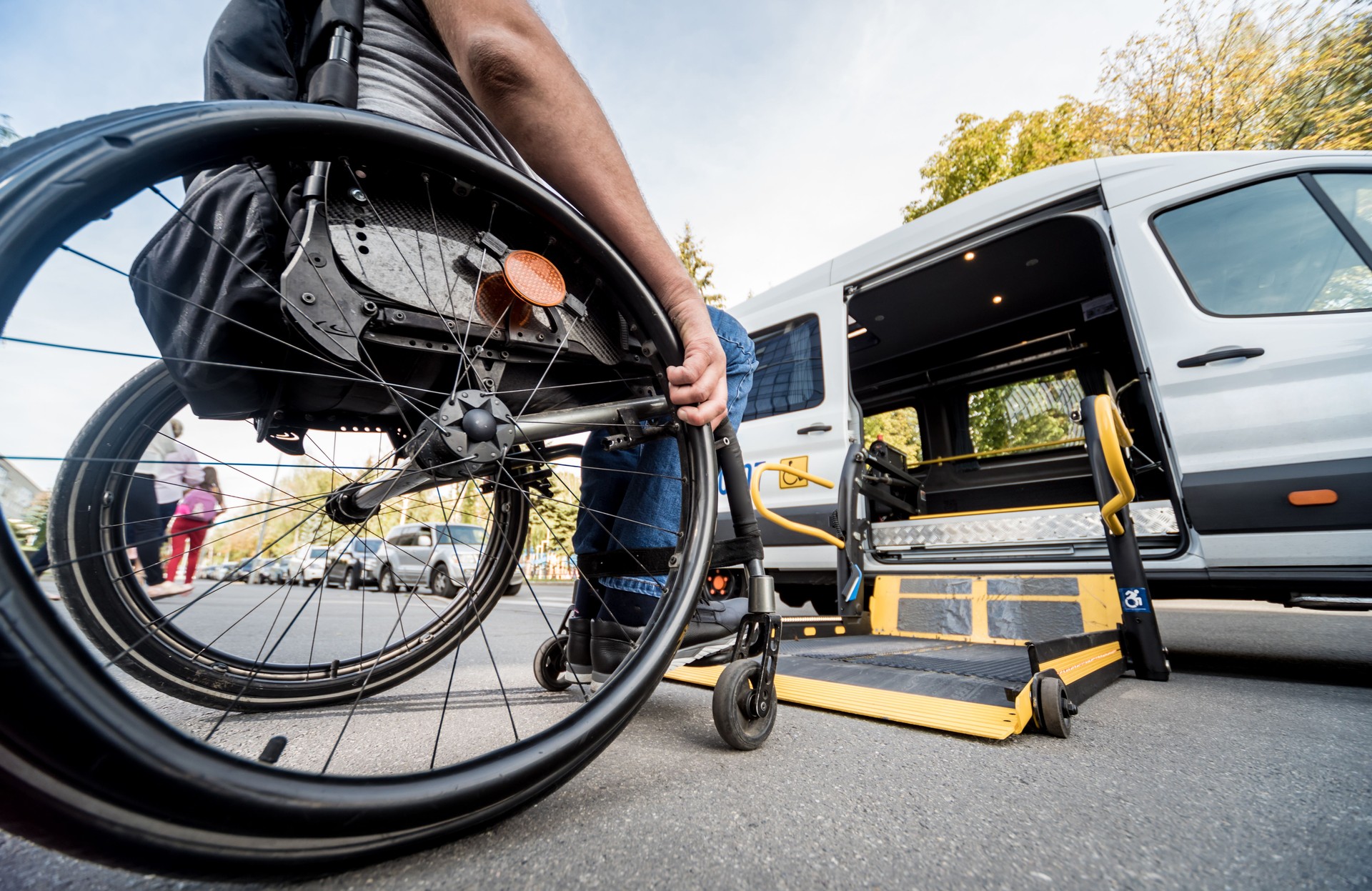 A man in a wheelchair moves to the lift of a specialized vehicle